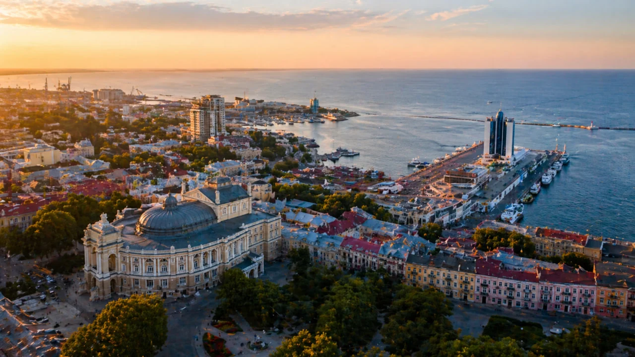 Панорама міської забудови, театру та морського порту в м’якому вечірньому світлі
